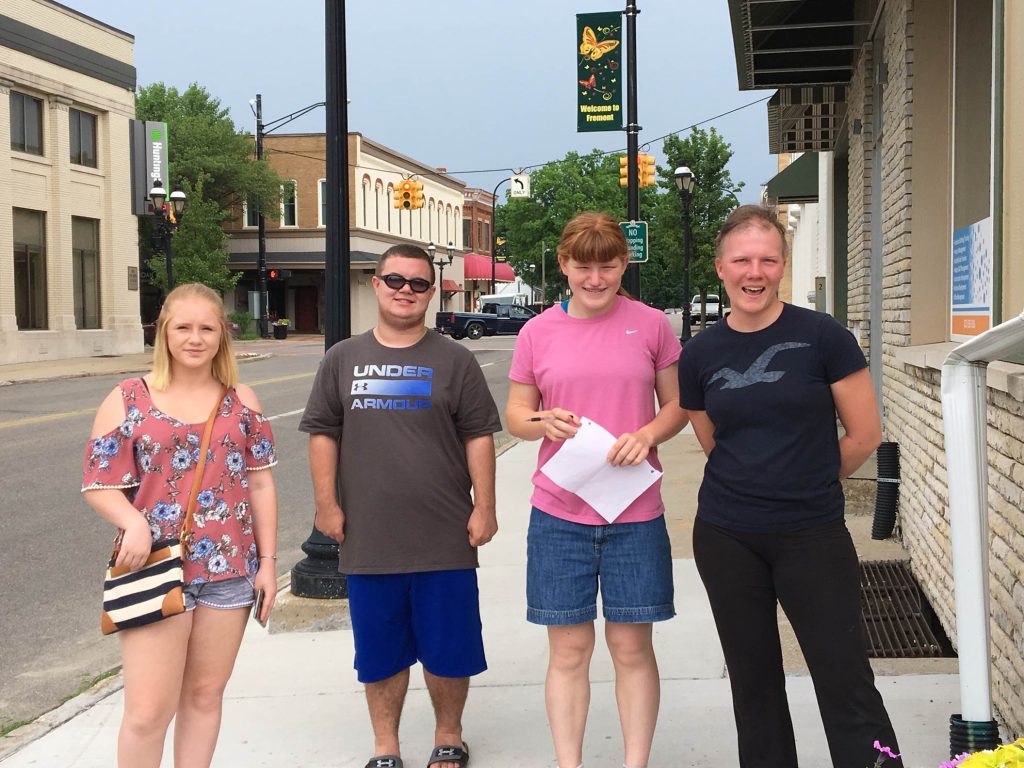 Four happy individuals posing together on a sunny day on a town street.