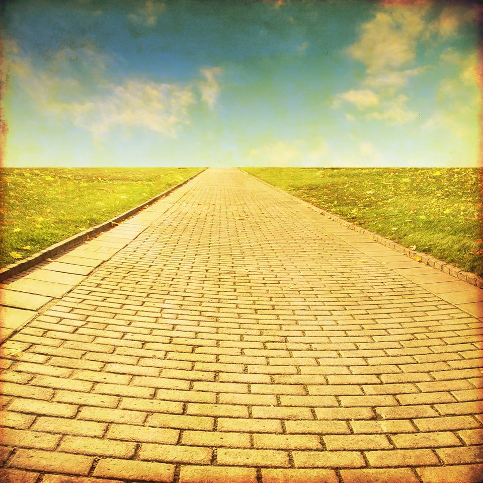 A faded and stylized image depicting a yellow brick road that leads into the distance, and a blue sky at the top.